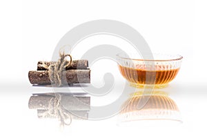 Cinnamon face pack isolated on white i.e. Cinnamon or tej powder well mixed with honey in a glass bowl and entire raw ingredients