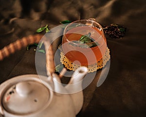 Cinnamon Green Tea Glass Cup with mint beside a white Pot