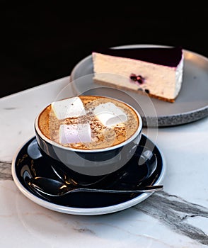 Cinnamon Latte with Marshmallows and Slice of Blueberry Cheesecake on Marble Table