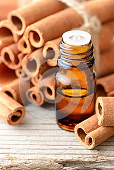 Cinnamon oil and cinnamon sticks on the wooden board