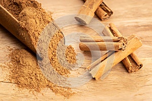 Cinnamon powder and cinnamon sticks in wooden scoop