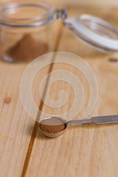 Cinnamon powder in measuring spoon close up with wooden neutral background