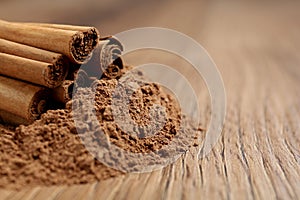 Cinnamon powder and sticks on wooden table, closeup. Space for text