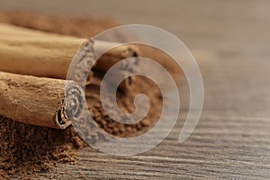 Cinnamon powder and sticks on wooden table, closeup. Space for text