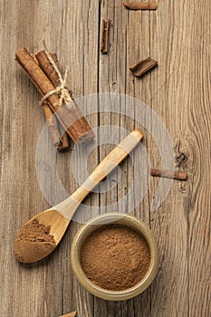 Cinnamon powder and sticks on a wooden table with copy space