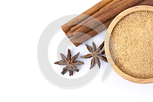 Cinnamon powder in wooden bowl and cinamon sticks with star anise isolated on white background.