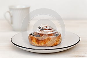 Cinnamon roll with raisins in a ceramic saucer