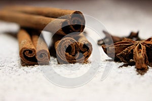 Cinnamon sticks and anise stars closeup on powdered sugar table. Cooking and baking background. Aromatic condiment and spices.