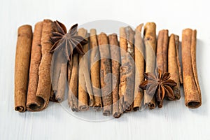 Cinnamon sticks and anise stars on white wooden background