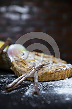 Cinnamon sticks on Apple pie at old textured wooden background