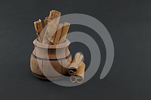 Cinnamon sticks bundle in wooden pot over black