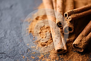 Cinnamon sticks and cinnamon powder on black slate plate