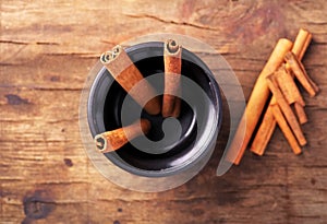 Cinnamon sticks in cup on old wooden background