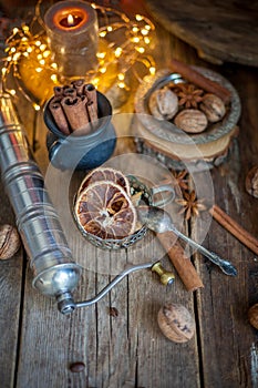 Cinnamon sticks, dried orange, star anise, aromatic spices on a wooden table. Christmas lights garlands. New Year`s still life.