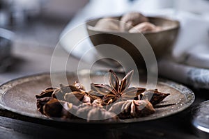 Cinnamon sticks, nutmeg and anise stars in cups over dark scorched wooden background