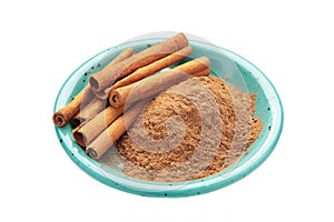 Cinnamon sticks and powder in blue plate isolated on white background