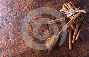 Cinnamon sticks and powder in spoon on a old copper table .