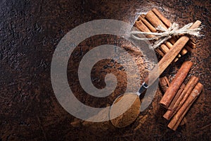 Cinnamon sticks and powder in spoon on a old copper table .