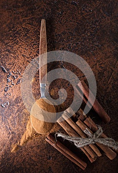 Cinnamon sticks and powder in spoon on a old copper table .