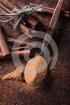 Cinnamon sticks and powder in spoon on a old copper table .