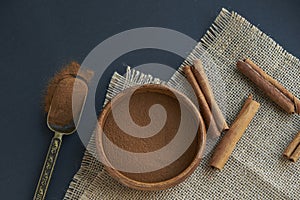 Cinnamon sticks, tied with jute rope in rustic style. Ground cinnamon in a wooden bowl and vintage scoop. Close up on a