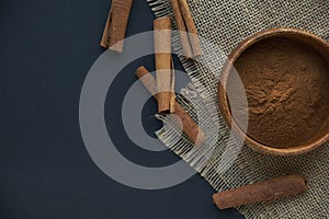 Cinnamon sticks, tied with jute rope in rustic style. Ground cinnamon in a wooden bowl and vintage scoop. Close up on a