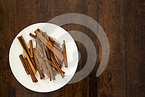 Cinnamon Sticks And White Plate On Wood Tabletop