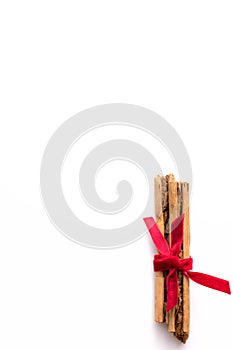 Cinnamon sticks wrapped in red velvet ribbon on a white background