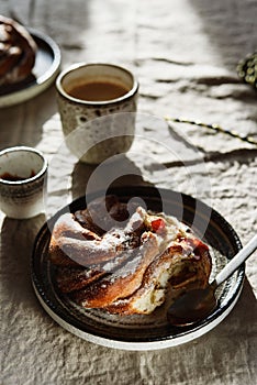 Cinnamon swirl brioche or Cinnamon roll bun and cups of cocoa on greige linen tablecloth