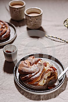 Cinnamon swirl brioche or Cinnamon roll bun and cups of cocoa on greige linen tablecloth