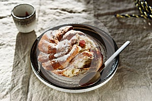 Cinnamon swirl brioche or Cinnamon roll bun and cups of cocoa on greige linen tablecloth