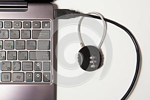 Cipher padlock on a network cable connecting laptop white on white background