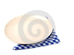 Circle beige ceramic plate over blue and white checkered fabric or napkin isolated on a white background.