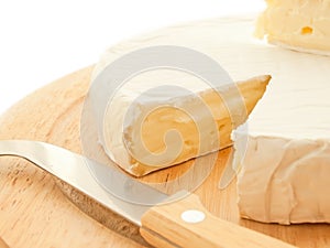 Circle Brie cheese on wooden desk with knife