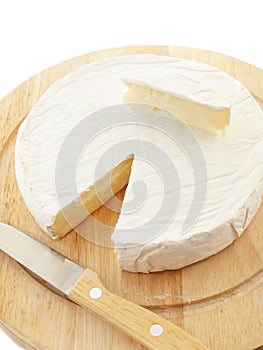 Circle Brie cheese on wooden desk with knife