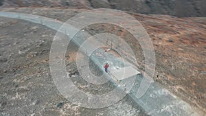 Circle flight around a women walking up a hill to the peak of a Mountain on Fuerteventura