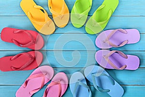 Circle of flip flops on blue painted beach decking, top view