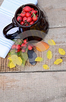 Circle hips on wooden boards next to autumn leaves and berries of wild rose and tea towel laid out