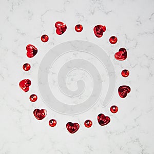 Circle made of hearts and red crystals on marble background with copy space, happy valentine`s day, mother`s day, flat lay, top