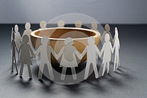 Circle of paper people holding hands in front of big empty bowl. Overpopulation, famine concept.
