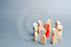 A circle of people surrounds a red person. Communication. Business team, teamwork, team spirit. Wooden figures of people. A circle