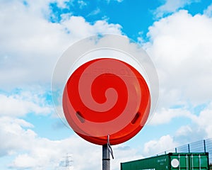 Circle Red lifebelt / Lifebuoy  dispenser on the shore of lake Manvers in Yorkshire against blue cloudy sky
