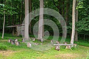 Circle of rustic benches in the woods around a fire pit with shack in background