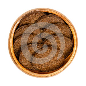 Circle shaped pumpernickel slices, dark brown rye bread, in a wooden bowl