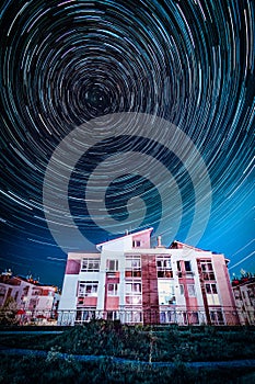 Circle star trails in the night sky above the houses