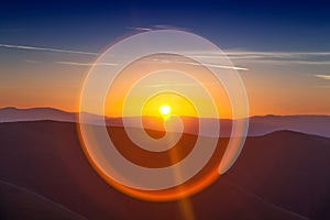 Circle sun reflexion at sunset over mountains