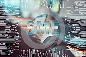 Circuit board on the background of a man working on a laptop and holding a smartphone in his hands. Caption:.SME, small and medium