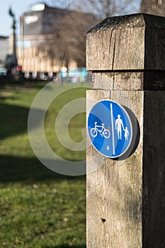 Circular blue shared cycle path sign for cyclists and pedestrians on a wooden post