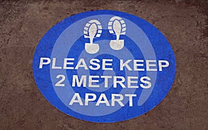 Circular blue sign on the ground with boot prints warning about dangers of coronavirus