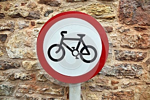 Circular cycling sign with bicycle icon with old stone wall background